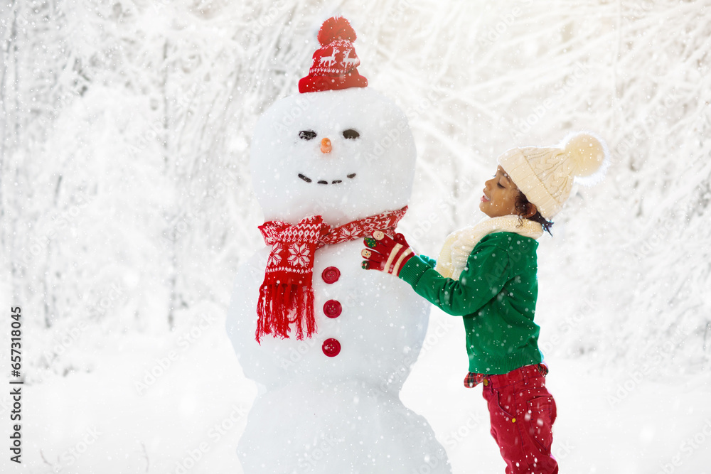 Child building snowman. Kids build snow man.