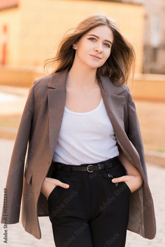 Portrait of a Caucasian attractive and happy young woman in casual clothes in the city while walking on a sunny day. The concept of style, fashion, youth and lifestyle