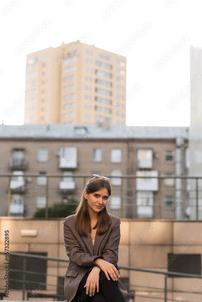 Portrait of a Caucasian attractive and happy young woman in casual clothes and sunglasses in the city while walking on a sunny day. The concept of style, fashion, youth and lifestyle