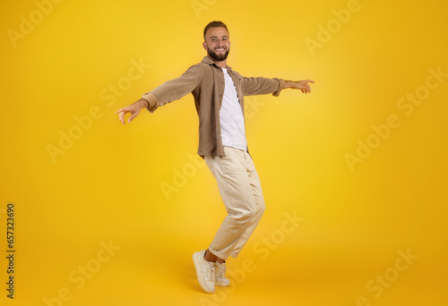 Smiling millennial caucasian guy with beard in casual has fun  dance  freezes in air