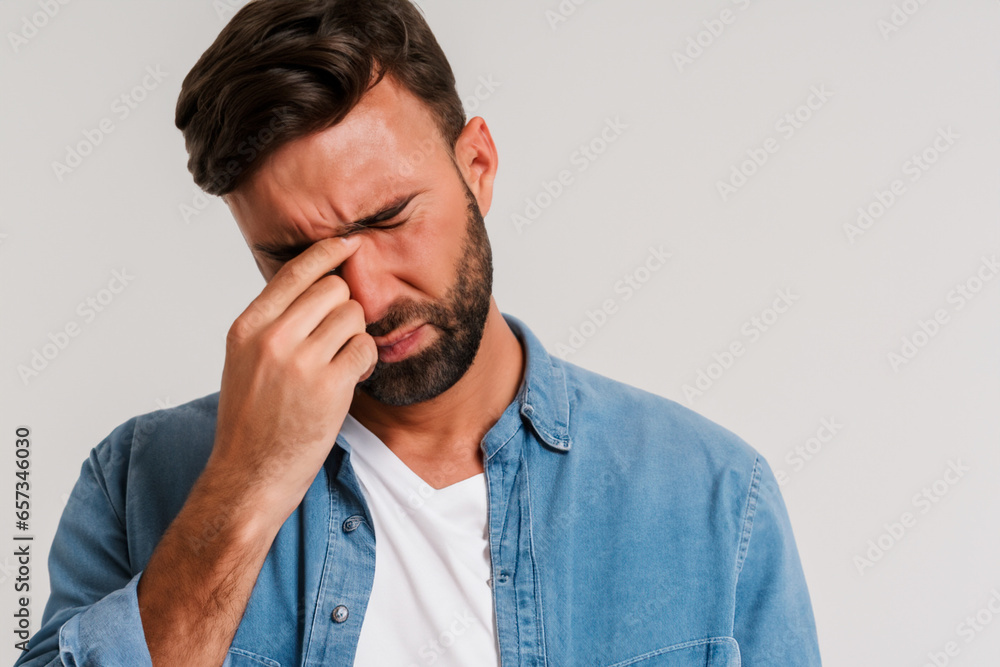 Caucasian man with closed eyes in blue shirt with severe headache Caucasian man with closed eyes in blue shirt with severe headache