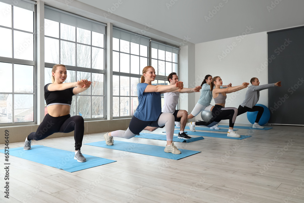 Group of sporty young people stretching in gym Group of sporty young people stretching in gym