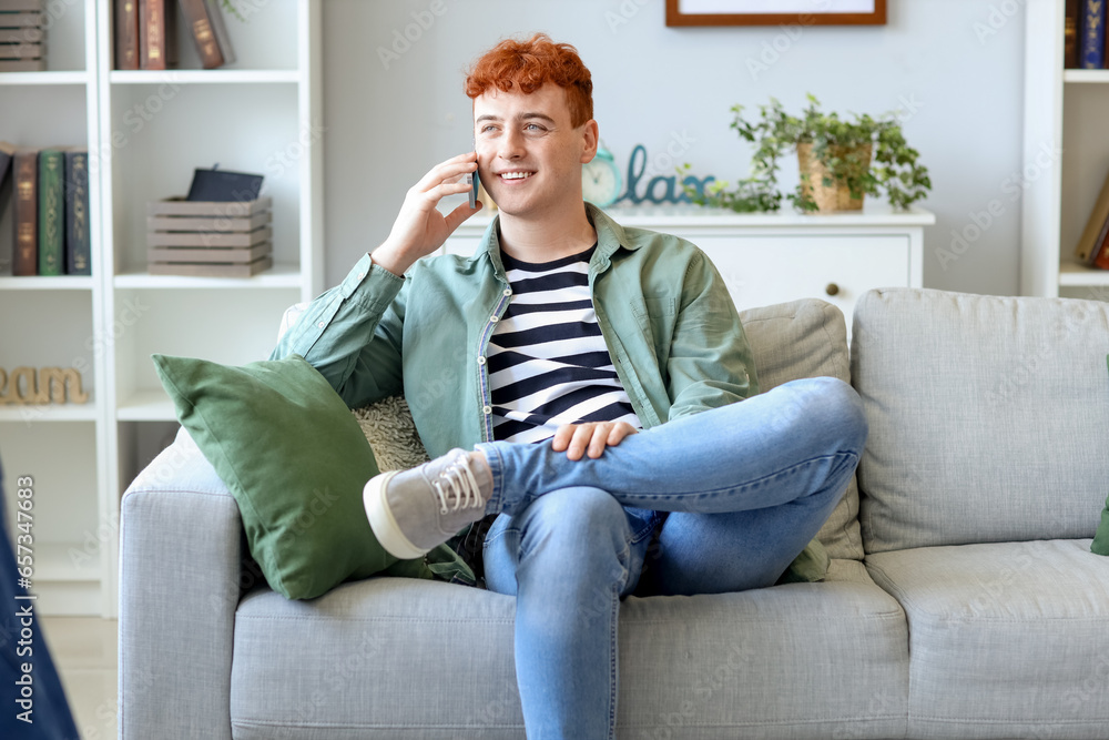 Young redhead man talking by mobile phone on sofa at home Young redhead man talking by mobile phone on sofa at home