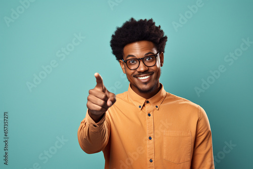 Young black man in glasses pointing finger against solid color background, happycore, studio location