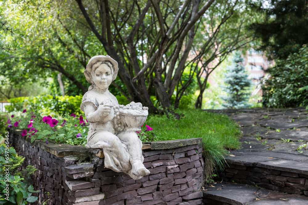 Statue in the garden. Sculpture of a little girl with a basket in a public park in Krasnoyarsk Russia