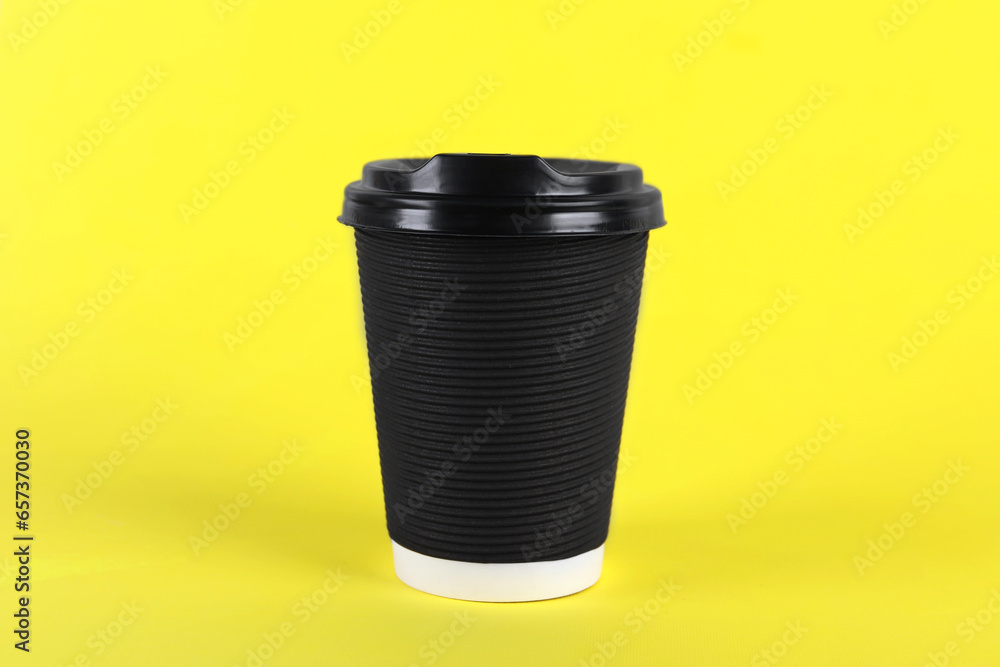 Black paper cup with plastic lid on yellow background. Coffee to go Black paper cup with plastic lid on yellow background. Coffee to go