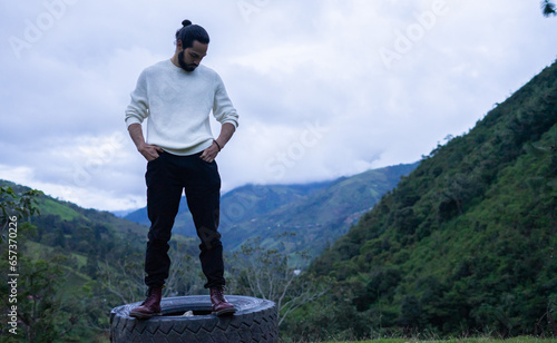 hombre de cabello largo con paisaje montañoso de fonso y sueter blanco photo