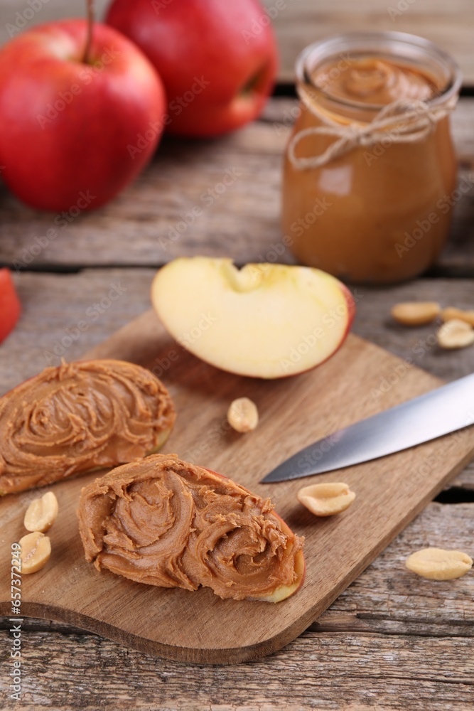 Fresh apples with peanut butter on wooden table