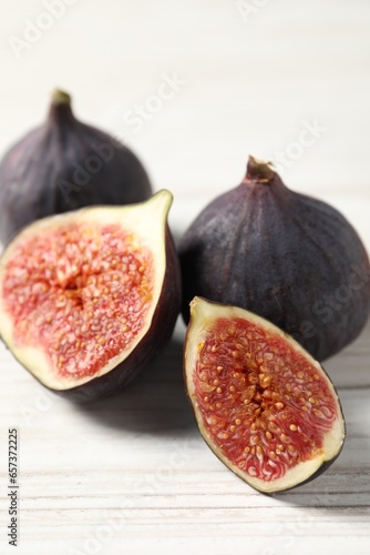 Whole and cut ripe figs on white wooden table, closeup