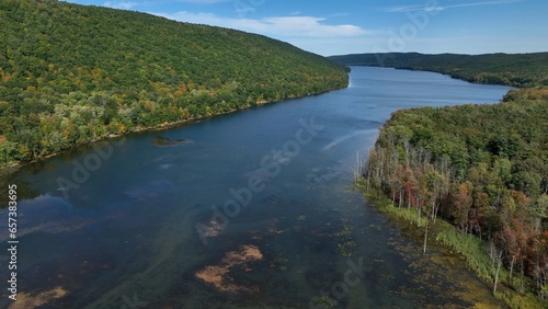 Peaceful calm mountain lake with sunlight reflecting on blue water beside green trees Canadice Finger Lake in Western New York state photo