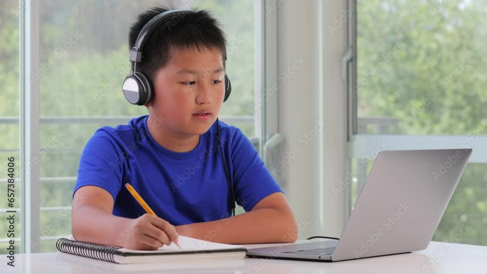 12 year old boy working on his school homework on his laptop while listening to music. 12 year old boy working on his school homework on his laptop while listening to music.
