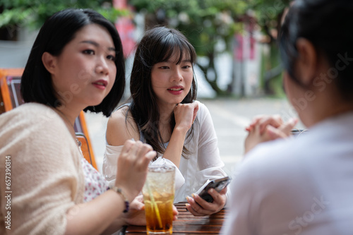 A group of happy young Asian girl friends are enjoying talking chitchat at a coffee shop in the city photo