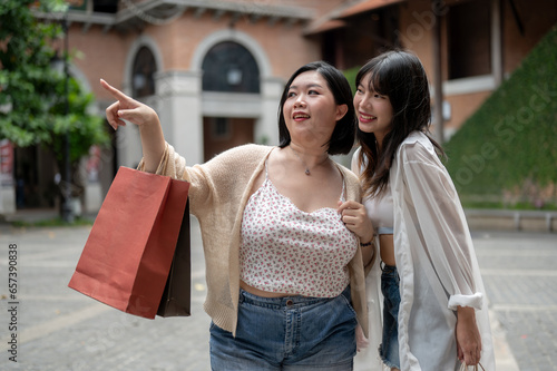 Two happy Asian female friends are enjoying their shopping day in the city together.