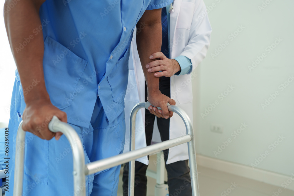 Physical therapist helps a male patient use a walker to practice walking. Support yourself from recovery from sore legs and ankles. Physical therapy service concept.