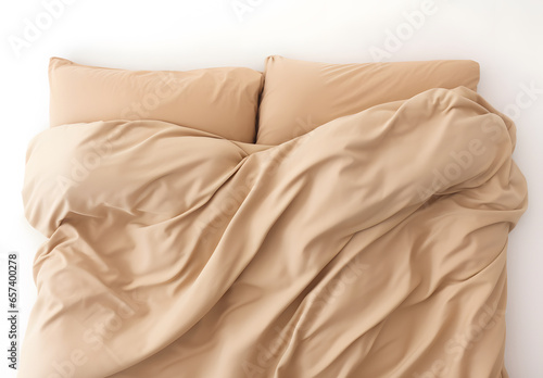 The head of a bed set done in tan sheets and pillow cases, isolated on white; messy comforter photo