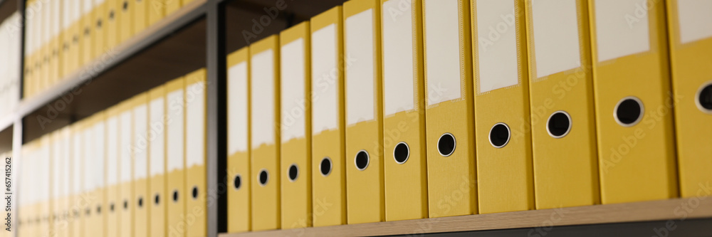 Yellow folders with materials put in long rows on shelves - obrazy, fototapety, plakaty 
