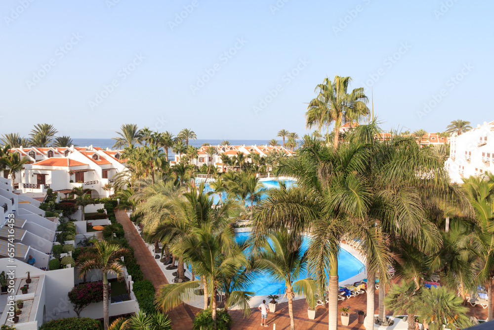 Hotel resort panorama with swimming pool, palm trees and view of the Atlantic Ocean in Playa de las Americas, Tenerife