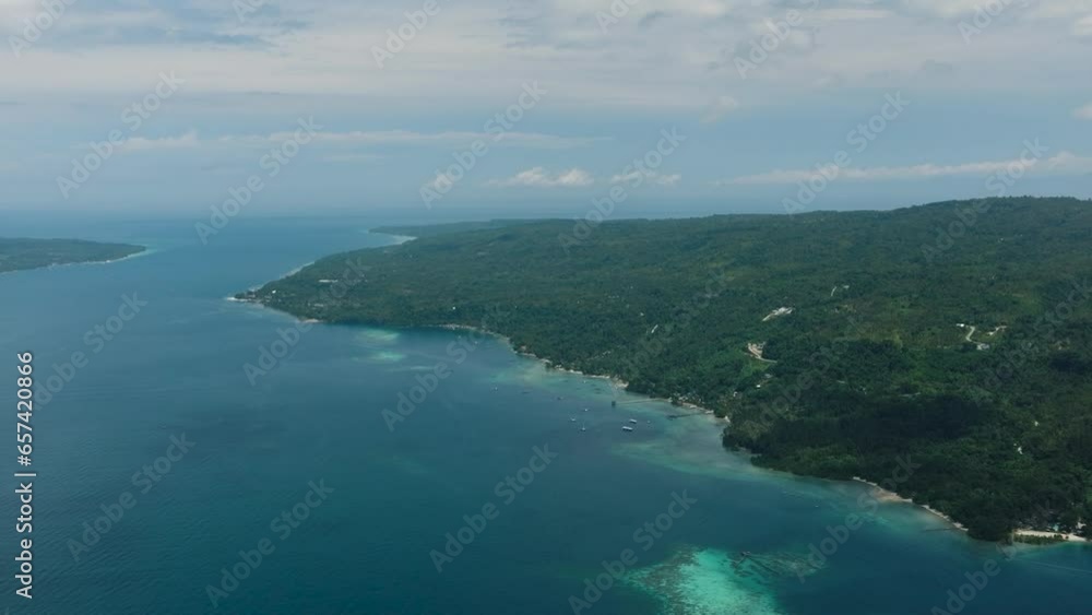 Top view of tropical island with green mountain and blue sea, sky and clouds. Samal Island. Davao, Philippines.