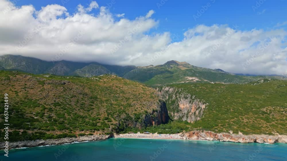 Aerial drone forward moving shot over tourists thronging along the secluded Gjipe Beach in Dhermi, Albania on a bright sunny day. Aerial drone forward moving shot over tourists thronging along the secluded Gjipe Beach in Dhermi, Albania on a bright sunny day.