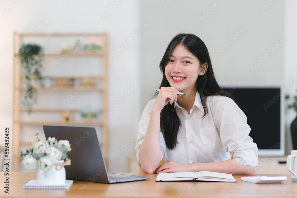 Young Asian female working with financial papers at home, using a calculator to count before paying taxes and receipts online. The millennial woman planning budget for saving money. Young Asian female working with financial papers at home, using a calculator to count before paying taxes and receipts online. The millennial woman planning budget for saving money.