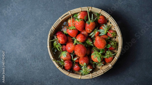 A container full of ripe strawberries on a dark background.