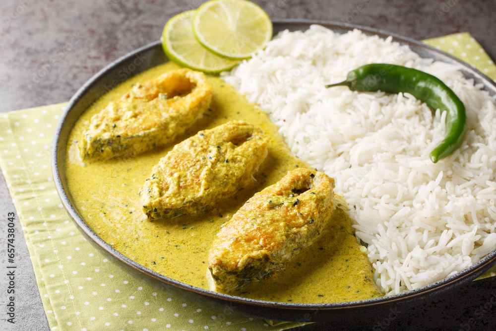 Bengali Shorshe Ilish or Hilsa cooked in Mustard Gravy served with white rice closeup on the plate on the table. Horizontal