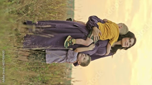vertical video portrait of a happy beautiful pregnant woman mother with two children on a walk at sunset in the summer close-up. High quality FullHD footage