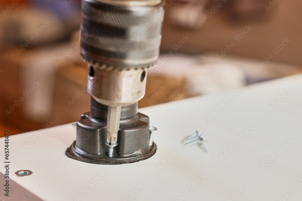 Furniture legs are attached with a screwdriver. Assembling cabinet furniture. Furniture legs are attached with a screwdriver. Assembling cabinet furniture.