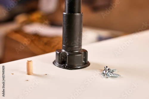 Furniture legs are attached with screws. Assembling cabinet furniture.
