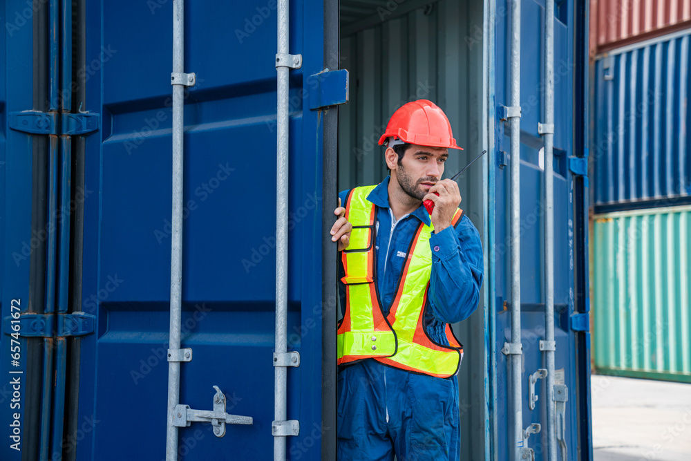 Male Container yard worker control and checking container at container yard warehouse. Logistics business. Import and export concept. Male Container yard worker control and checking container at container yard warehouse. Logistics business. Import and export concept.