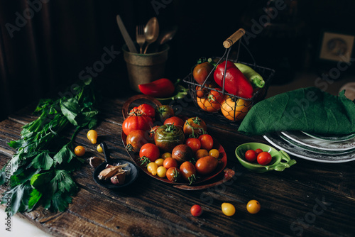 Still life, different varieties of tomato scattered on a wooden table, soft morning light, top view photo