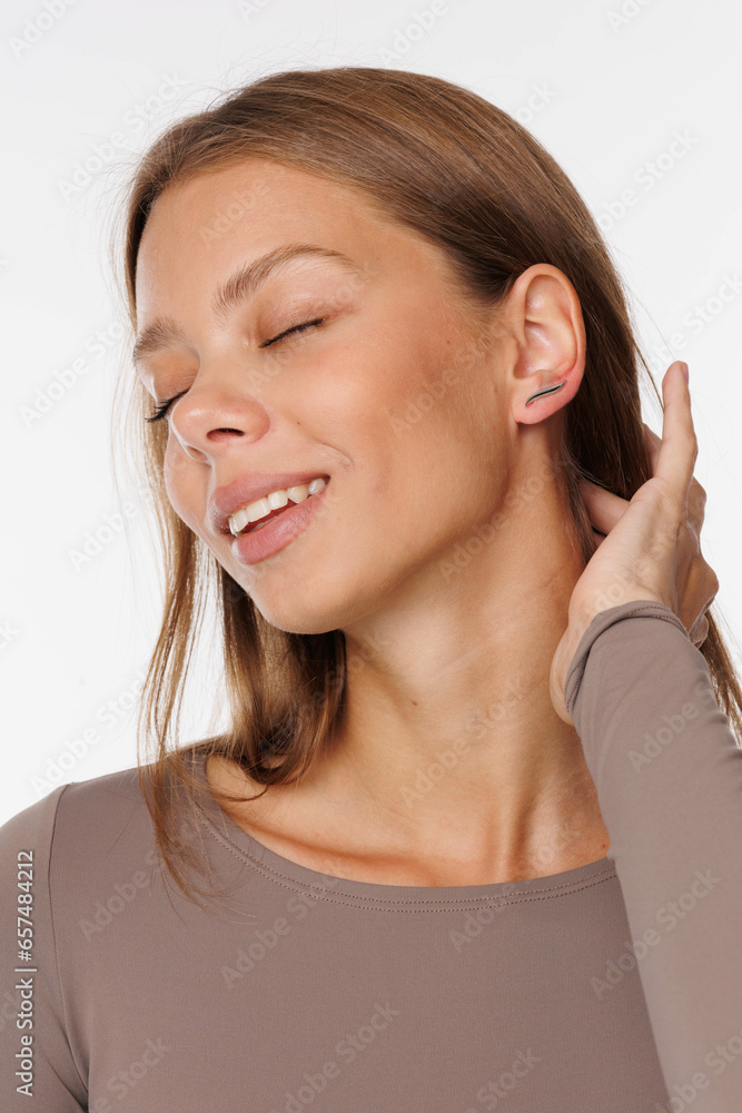 Beautiful young girl with fresh healthy skin. Woman advertise ear-rings. White background. Earrings, ear caffs closeup. Blond european woman with long hair with big lips, pretty smile. Cosmetology