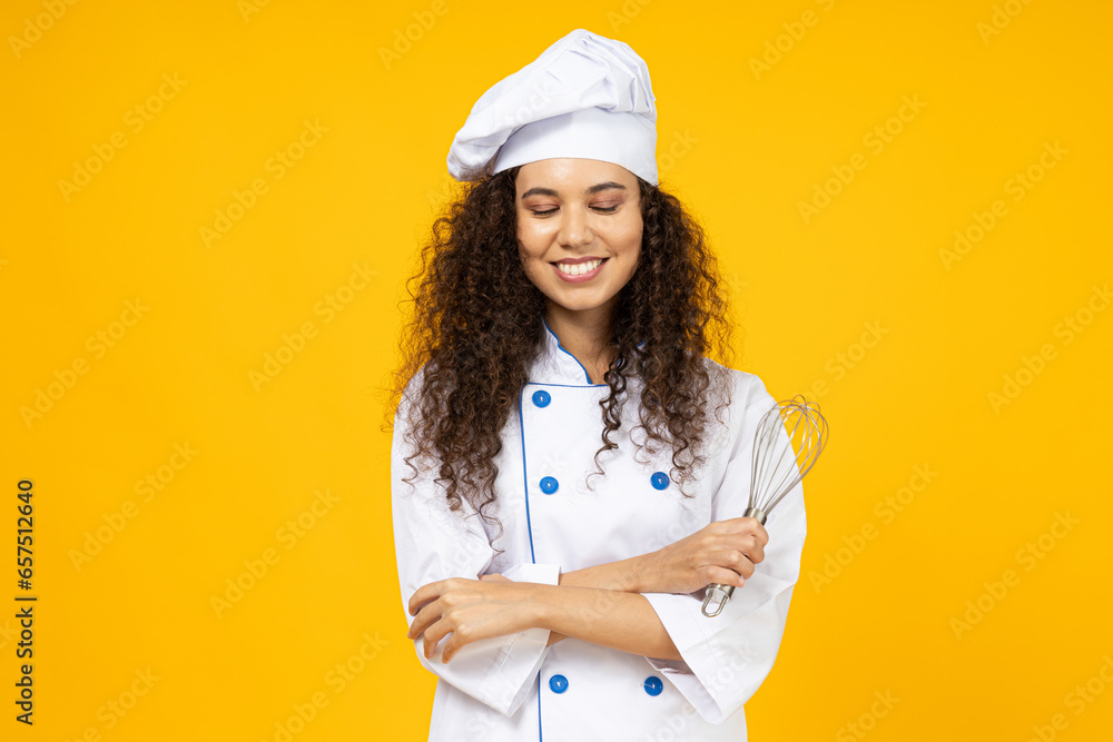 An attractive young girl in the uniform of a chef with a whisk in her hand