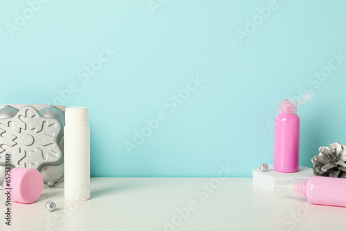 Cosmetic bottles and pine cone on blue background  space for text