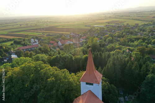 Flying above old whitewashed reformed church and aerial. Medieval landmark, Bicfalau, Szeklerland, Romania photo