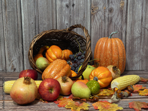 Autumn still life . Different fruits , vegetables an pumpkin in the wicker basket on the wooden table