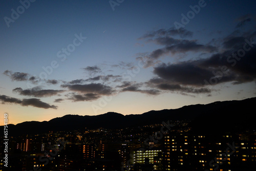 Fototapeta Naklejka Na Ścianę i Meble -  夕日が沈んだ後のマジックアワー。空はオレンジ色に染まり街の明かりが灯る。神戸市内より六甲山系をのぞむ。
