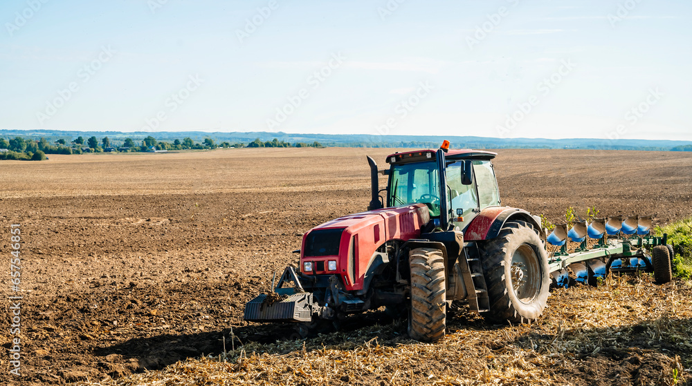 Fototapeta premium Tractor in the field. Agricultural machinery. Agricultural farm tractor during tillage of soil and field after harvest.