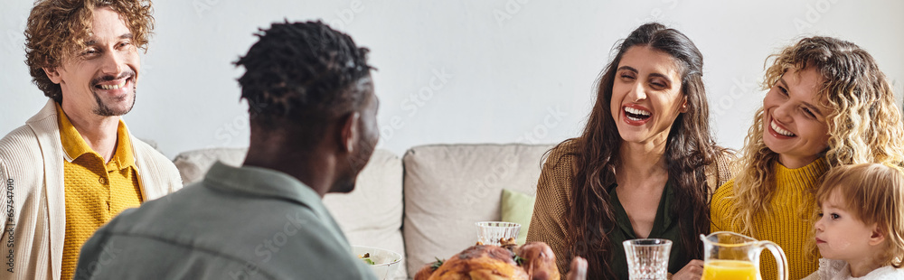 happy multiethnic friends talking near toddler girl during Thanksgiving celebration, banner happy multiethnic friends talking near toddler girl during Thanksgiving celebration, banner