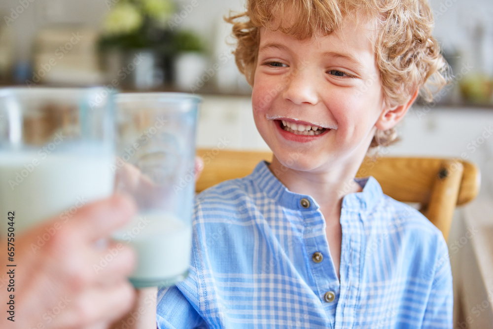 Happy boy toasting milk glass with mother Happy boy toasting milk glass with mother