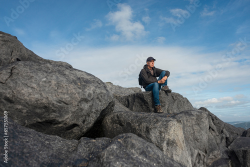 Male backpacker sitting on rocks enjoying the view after walking up a mountain