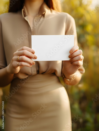 A woman's hands hold a blank business card as a mock-up for showcasing a design, style beige aesthetic, minimalist, delicate and feminine