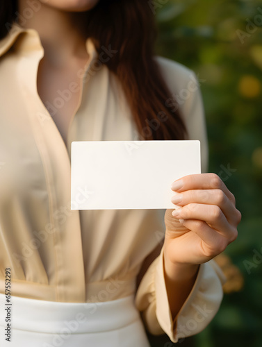 A woman's hands hold a blank business card as a mock-up for showcasing a design, style beige aesthetic, minimalist, delicate and feminine