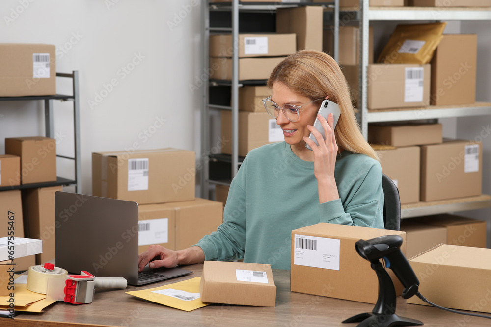 Seller talking on phone while working in office. Online store Seller talking on phone while working in office. Online store