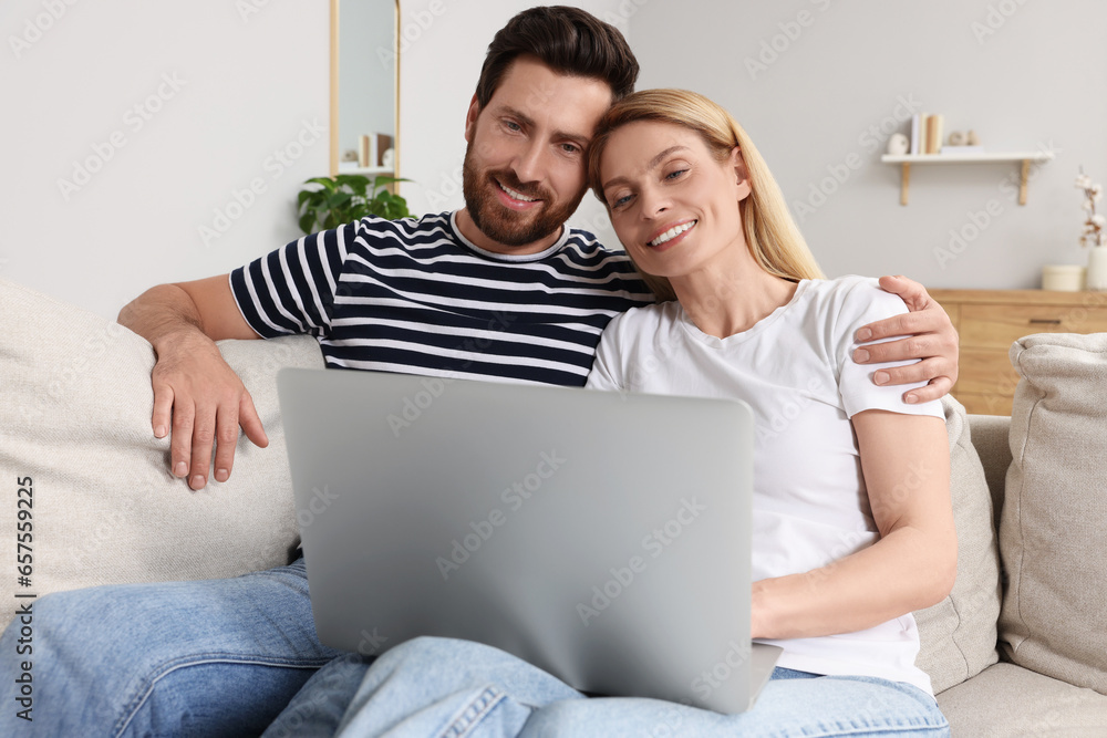 Happy couple with laptop on sofa at home Happy couple with laptop on sofa at home