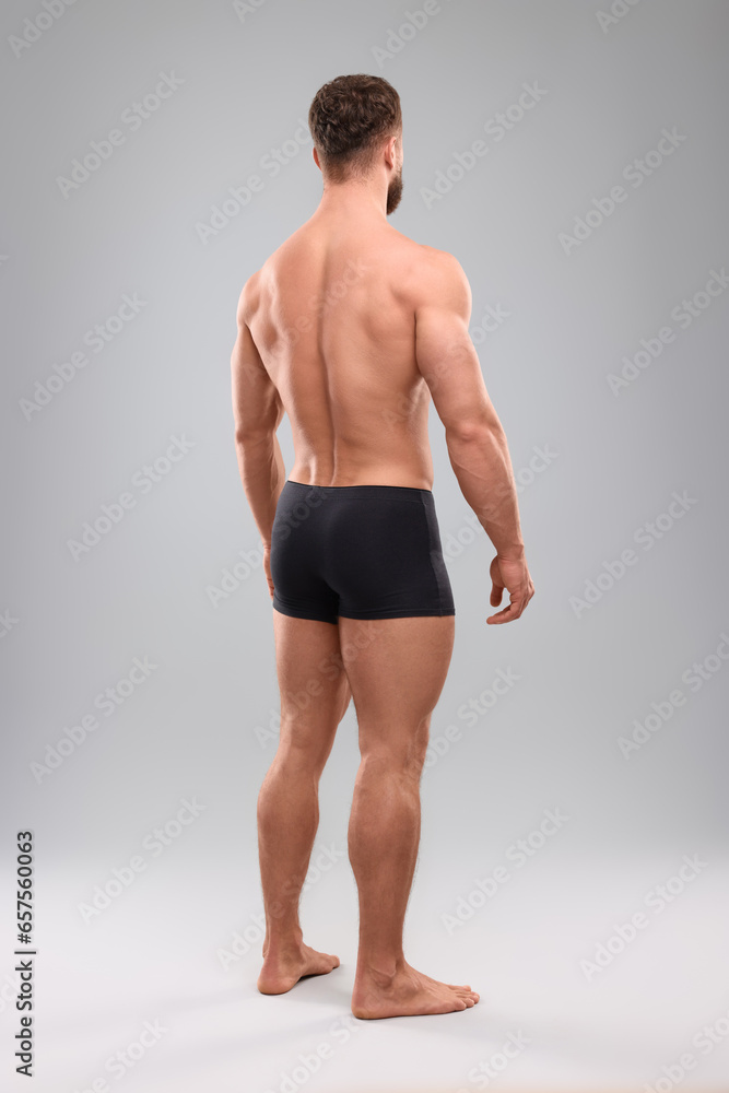 Muscular man on light grey background, back view. Sexy body