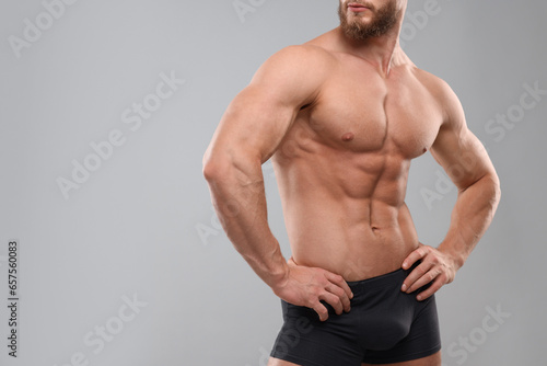 Muscular man showing abs on light grey background, closeup and space for text. Sexy body