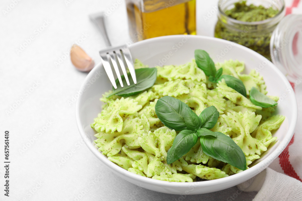 Delicious pasta with pesto sauce and basil served on light table, closeup. Space for text
