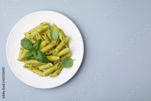 Delicious pasta with pesto sauce and basil on light grey background, top view. Space for text