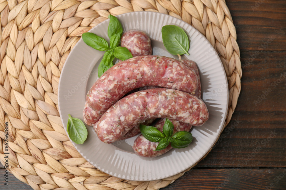 Raw homemade sausages and basil leaves on wooden table, top view Raw homemade sausages and basil leaves on wooden table, top view